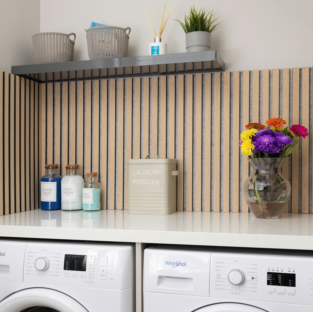Laundry room with folded towels on a shelf and a basket of clean clothes
